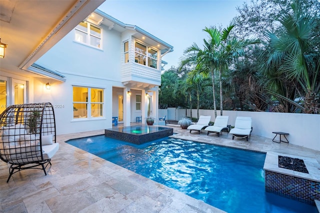 pool at dusk featuring a patio and an outdoor living space with a fire pit