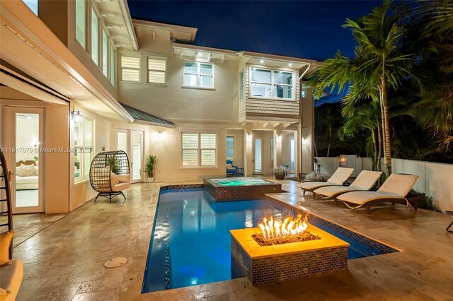 pool at twilight with a fire pit, an in ground hot tub, and a patio area