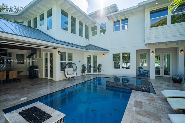 rear view of property featuring a patio, a pool with hot tub, and french doors