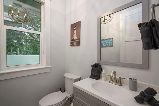 bathroom featuring toilet, vanity, and an inviting chandelier