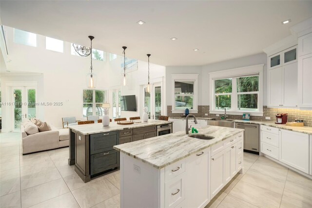 kitchen featuring decorative light fixtures, dishwasher, a healthy amount of sunlight, and a center island with sink