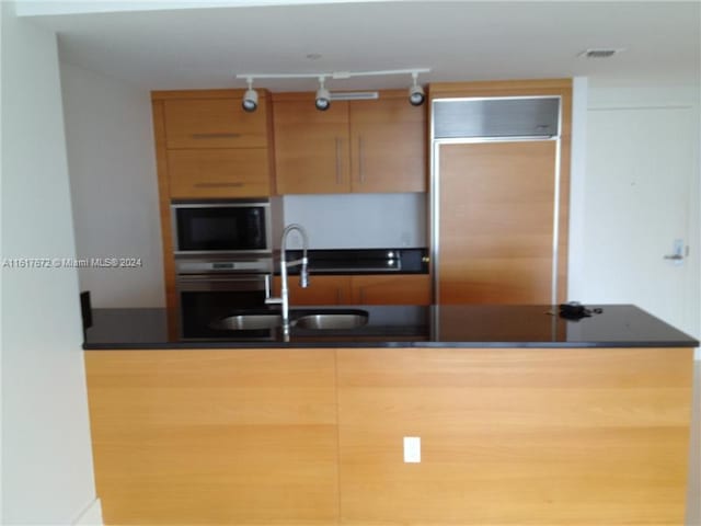 465 Brickell Ave Unit 3706, Miami, FL 33131 - kitchen featuring built in appliances, dark countertops, a sink, and track lighting