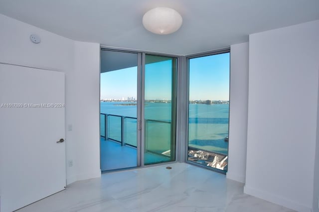 unfurnished room featuring a water view and a wall of windows