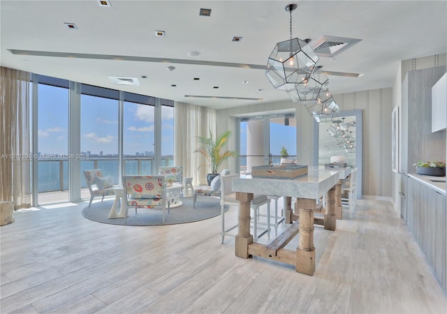 dining space featuring floor to ceiling windows, a water view, and light hardwood / wood-style flooring