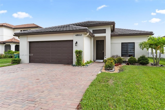 prairie-style house with stucco siding, a tiled roof, an attached garage, decorative driveway, and a front yard