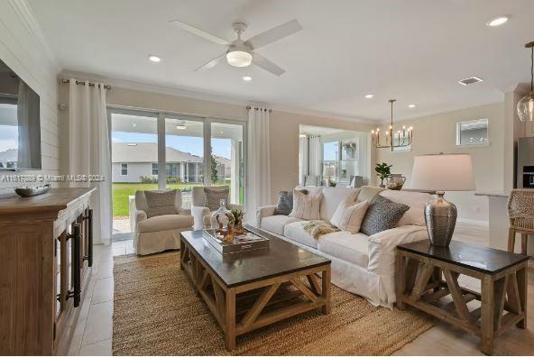 tiled living room featuring ceiling fan with notable chandelier and ornamental molding