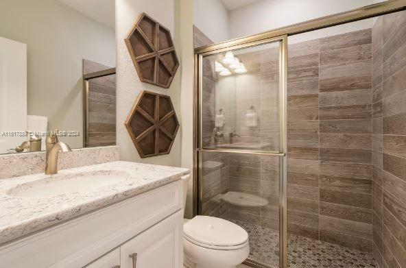 bathroom featuring vanity, walk in shower, and toilet