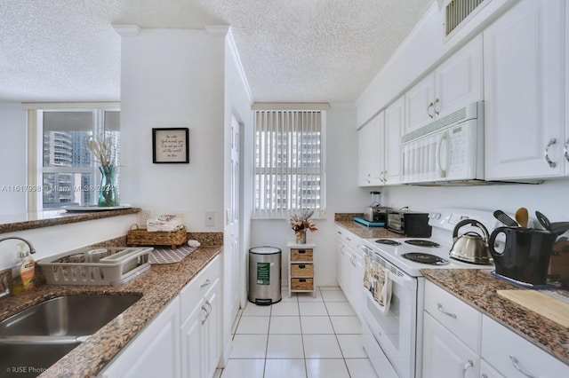 kitchen with a textured ceiling, white appliances, white cabinetry, and a wealth of natural light