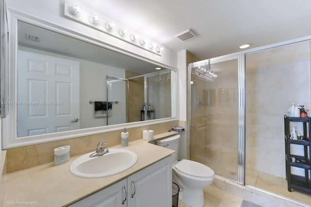 bathroom featuring tile patterned flooring, vanity, toilet, and a shower with door