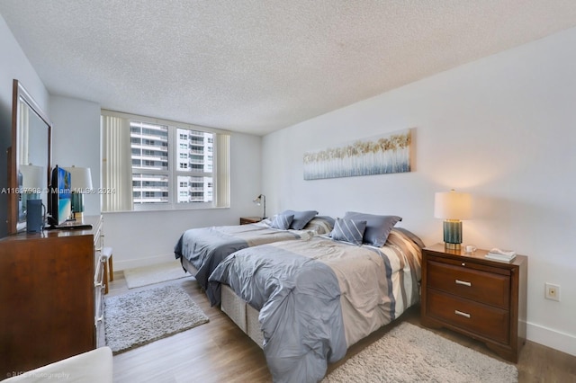 bedroom featuring a textured ceiling and light hardwood / wood-style floors