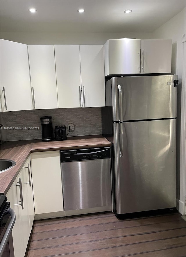 kitchen with white cabinetry, dark hardwood / wood-style floors, backsplash, and appliances with stainless steel finishes