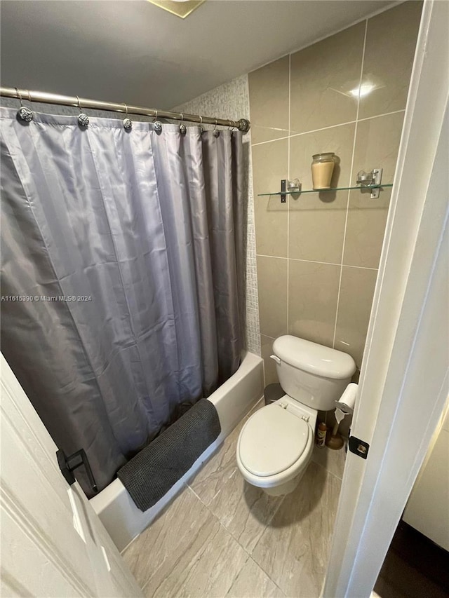 bathroom with tile patterned flooring, tile walls, toilet, and shower / bath combination with curtain