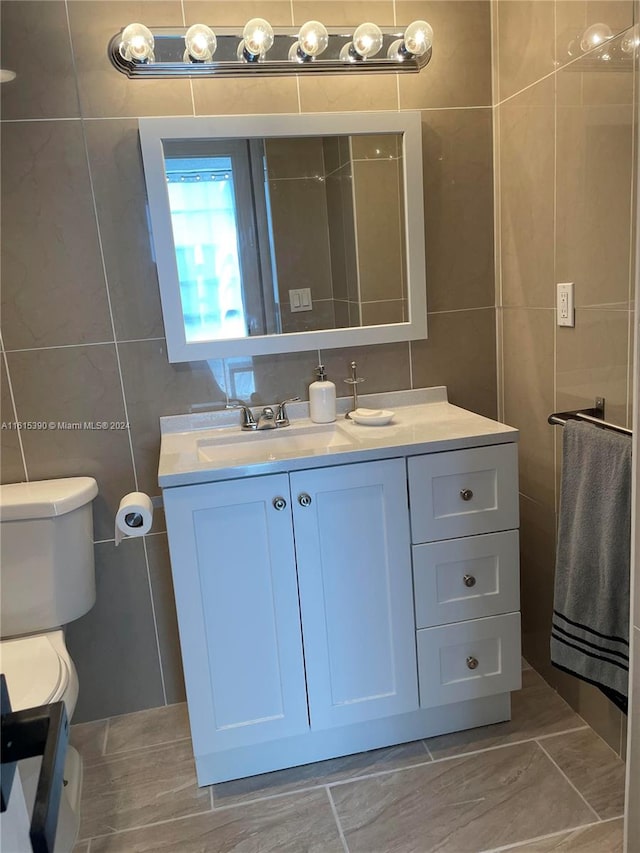 bathroom with tile patterned floors, vanity, tile walls, and toilet