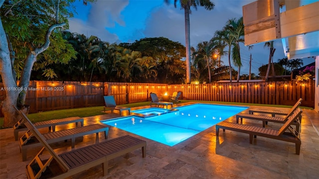 pool at dusk with a patio area and an in ground hot tub