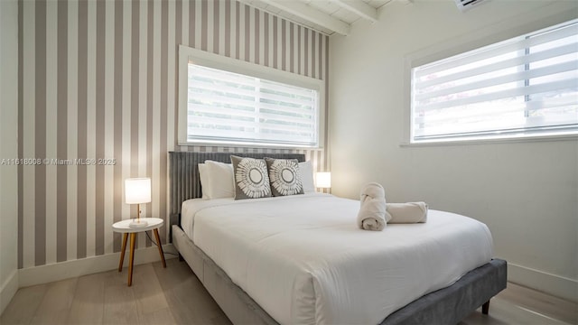 bedroom featuring beam ceiling and light wood-type flooring