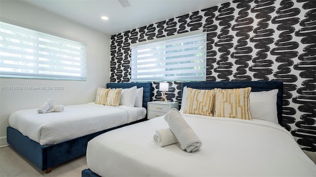 bedroom featuring multiple windows, hardwood / wood-style floors, and ceiling fan