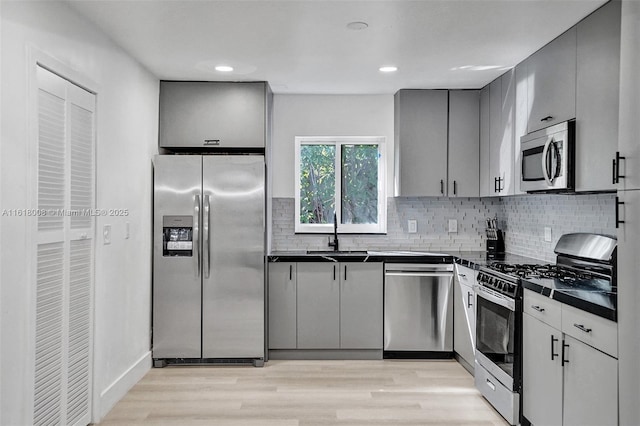 kitchen featuring tasteful backsplash, appliances with stainless steel finishes, gray cabinets, and light wood-type flooring