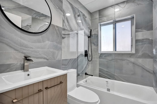 full bathroom featuring tiled shower / bath combo, vanity, tile walls, and toilet