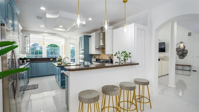 kitchen featuring a kitchen island, decorative backsplash, blue cabinetry, light tile patterned flooring, and wall chimney exhaust hood