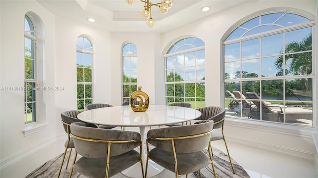 dining area with tile patterned floors, an inviting chandelier, and a tray ceiling