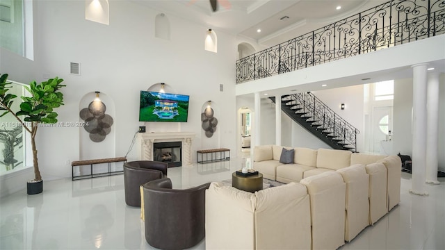 living room featuring crown molding, ornate columns, a high ceiling, and a fireplace