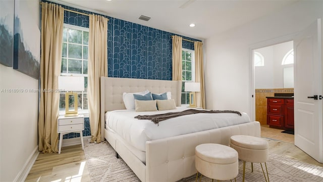 bedroom featuring ensuite bathroom and light wood-type flooring