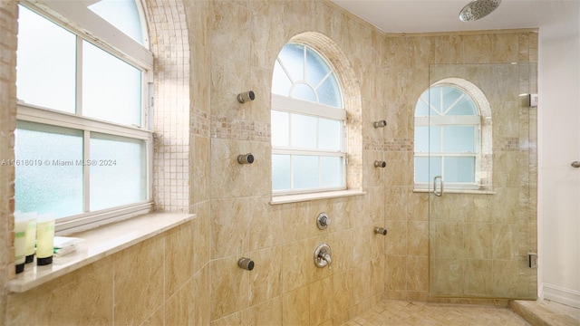 bathroom featuring tiled shower, tile patterned flooring, and a wealth of natural light