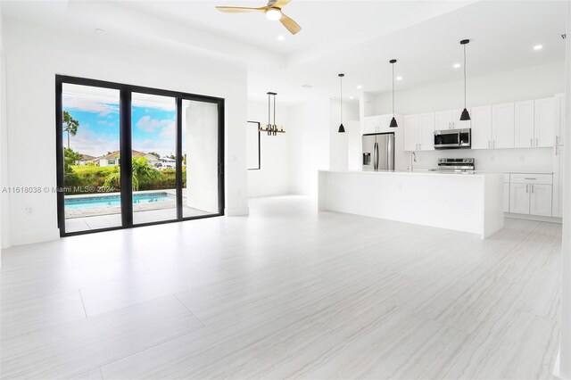 unfurnished living room featuring ceiling fan with notable chandelier and sink