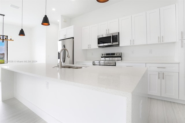 kitchen with light stone counters, stainless steel appliances, decorative light fixtures, and white cabinets