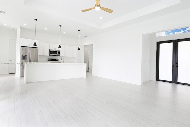 unfurnished living room featuring sink, french doors, ceiling fan, and a high ceiling