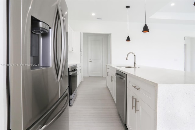 kitchen with pendant lighting, appliances with stainless steel finishes, sink, and white cabinets