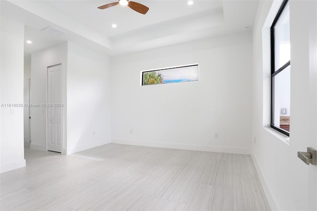 unfurnished room featuring ceiling fan and a raised ceiling