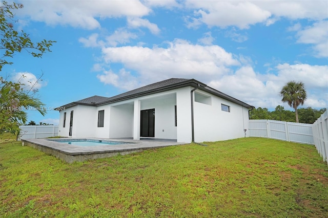 back of property with a fenced in pool, a patio, and a lawn