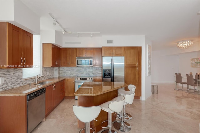 kitchen with a kitchen bar, tasteful backsplash, stainless steel appliances, sink, and a kitchen island