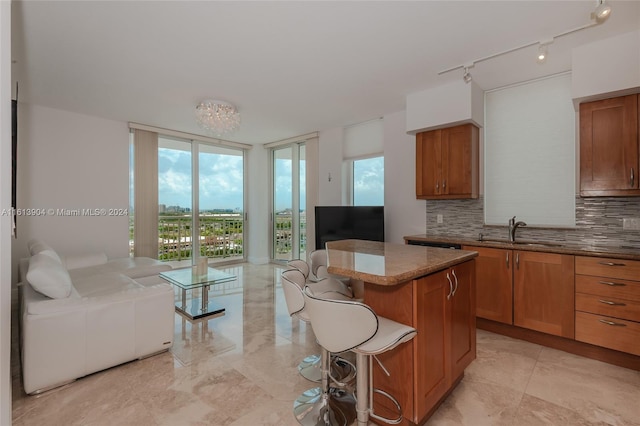 kitchen with decorative backsplash, a breakfast bar, sink, a wall of windows, and a kitchen island