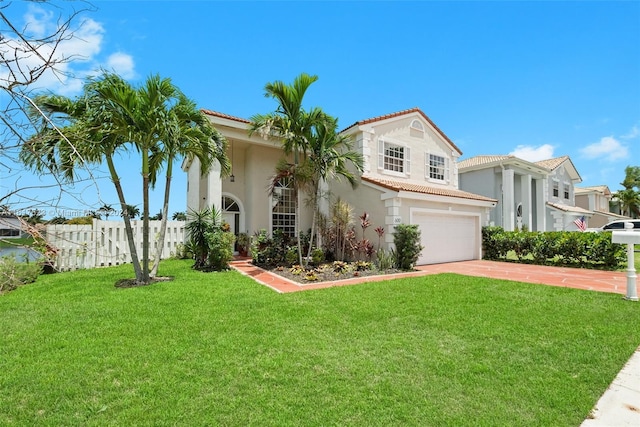 mediterranean / spanish-style house featuring fence, a tile roof, driveway, stucco siding, and a front yard