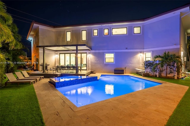 back house at twilight featuring a patio and a swimming pool with hot tub