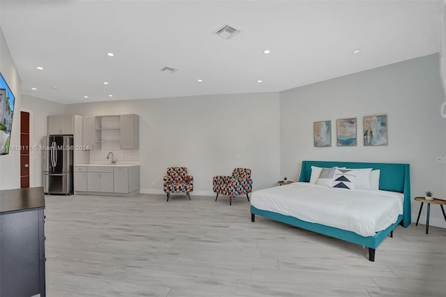 bedroom featuring stainless steel refrigerator, light hardwood / wood-style floors, and sink