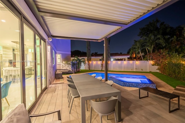 pool at twilight with a patio and an in ground hot tub