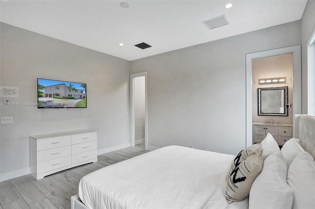 bedroom with light hardwood / wood-style flooring and ensuite bath