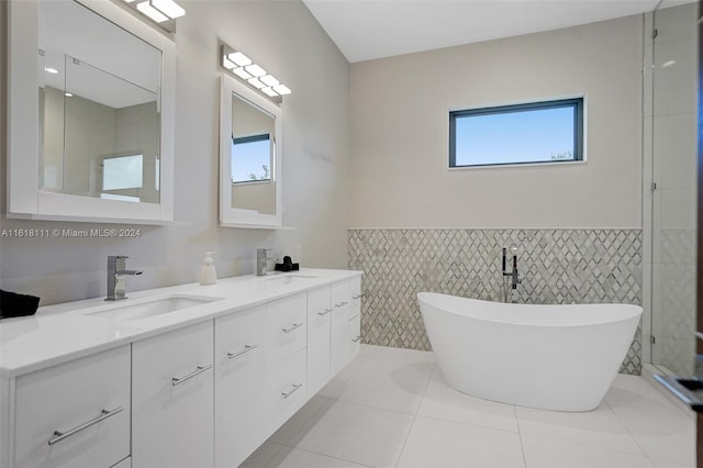 bathroom with tile patterned floors, tile walls, vanity, and a bathing tub