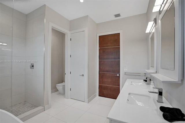 bathroom featuring tile patterned floors, a tile shower, vanity, and toilet