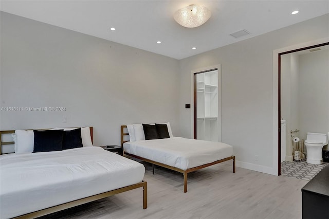 bedroom with connected bathroom, a walk in closet, and light hardwood / wood-style floors