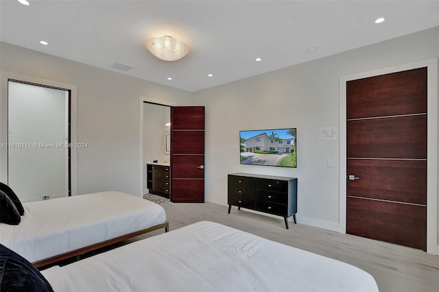 bedroom featuring light hardwood / wood-style flooring and connected bathroom