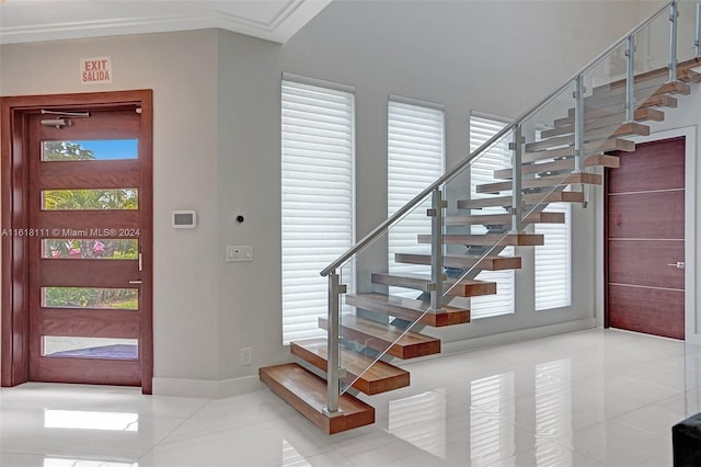 entrance foyer featuring light tile patterned flooring and crown molding