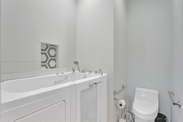 bathroom featuring toilet and a tub to relax in