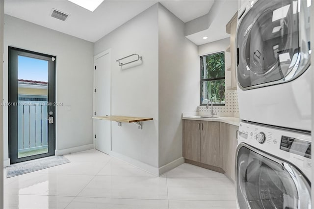 washroom featuring plenty of natural light, stacked washer and dryer, light tile patterned floors, and sink