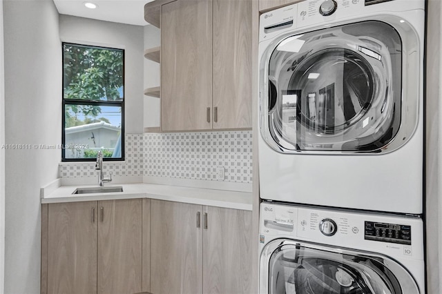 laundry area with cabinets, stacked washer and dryer, and sink