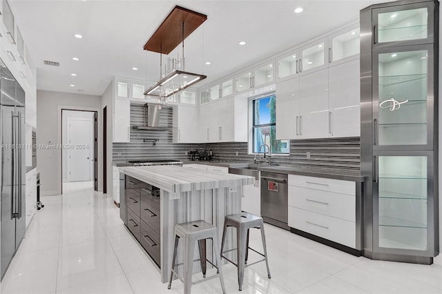 kitchen featuring backsplash, dishwasher, a kitchen island, white cabinets, and hanging light fixtures