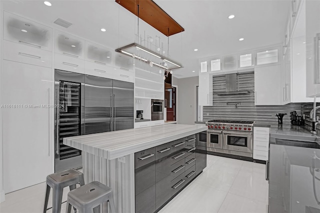 kitchen featuring a center island, white cabinetry, high end appliances, a kitchen breakfast bar, and decorative light fixtures